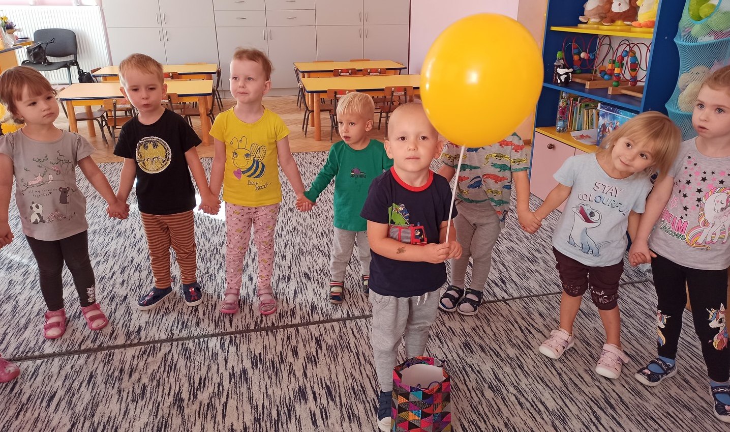 chłopiec z żółtym balonikiem stoi w kole pośród dzieci.jpg