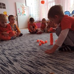 chłopiec układa wieżę z pomarańczowych klocków.jpg