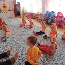 przedszkolaki na dywanie kladą pomarańczowe klocki na głowę.jpg