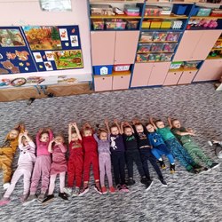 dzieci w kolorowych ubraniach leżą na dywanie jedno obok drugiego.jpg