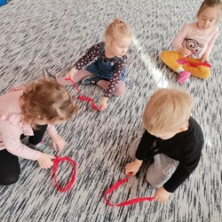 dzieci bawią się czerwoną bibułką na dywanie.jpg