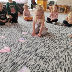dzieci na dywanie patrzą na dziewczynkę układającą serca.jpg