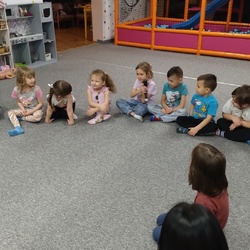 Dzieci siedzą na dywanie i przekazują sobie mikrofon.jpg
